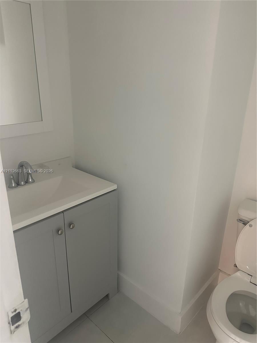 Grey shaker-style vanity with a solid-surface integrated countertop, brushed metal faucet, and wall-mounted mirror