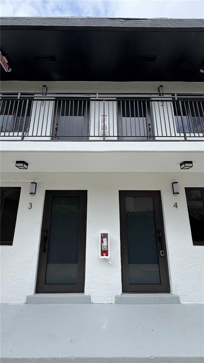 Two-story exterior featuring a stucco facade, private balcony with metal railings, and full-lite glass entry doors