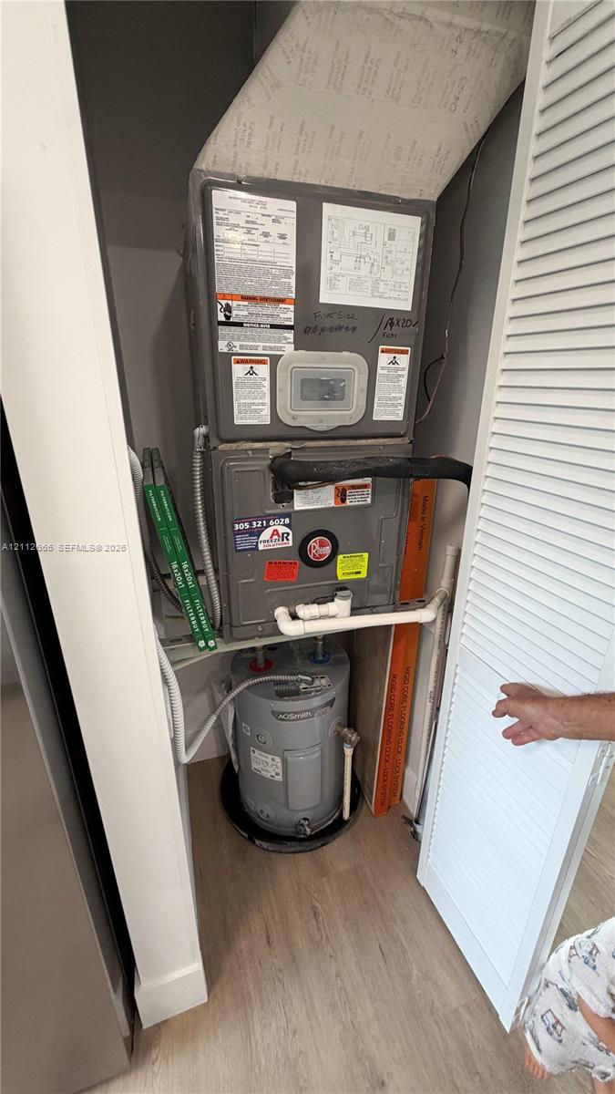 Mechanical closet housing a gas furnace unit and electric water heater, enclosed by louvered doors