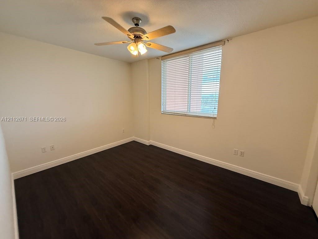 Interior space featuring wood-finish flooring, neutral wall paint, a ceiling fan with integrated lighting, and a window equipped with horizontal blinds