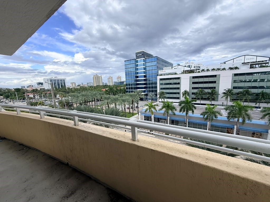 Covered balcony featuring concrete flooring and a white metal safety railing