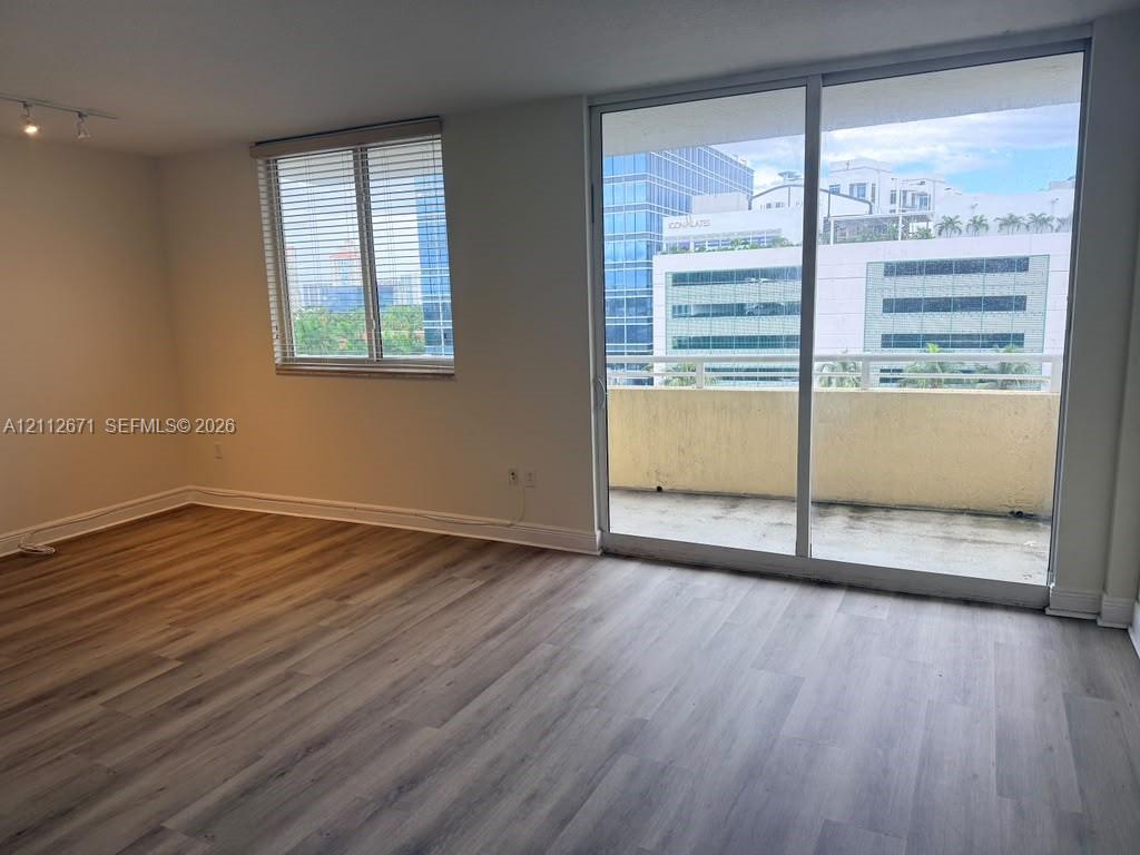 Wood-finish flooring, sliding glass door, private balcony, and multi-pane window with blinds Wood-finish flooring, sliding glass door, private balcony, and multi-pane window with blinds