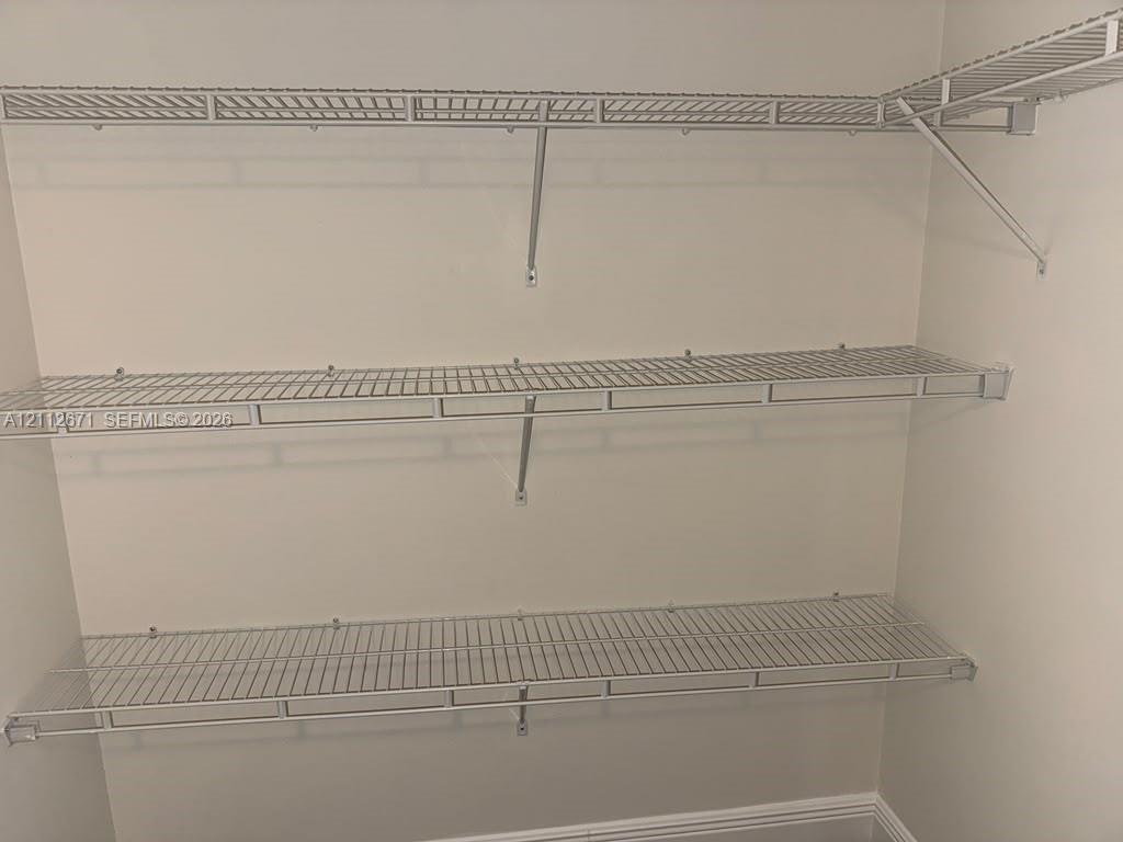 Wall-mounted white wire shelving system featuring three tiered levels of storage