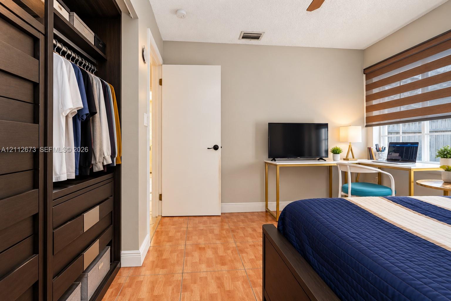 Built-in dark wood-finish cabinetry, neutral wall paint, tile flooring, and multi-layered window shades