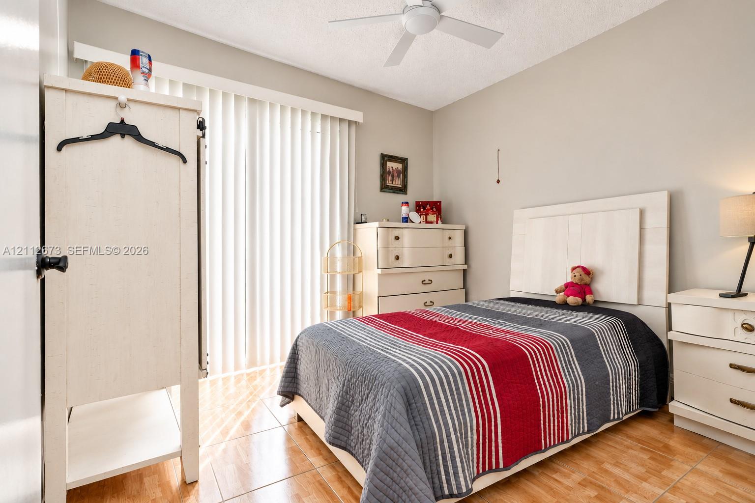 Ceramic tile flooring, white ceiling fan with integrated lighting, and vertical window blinds