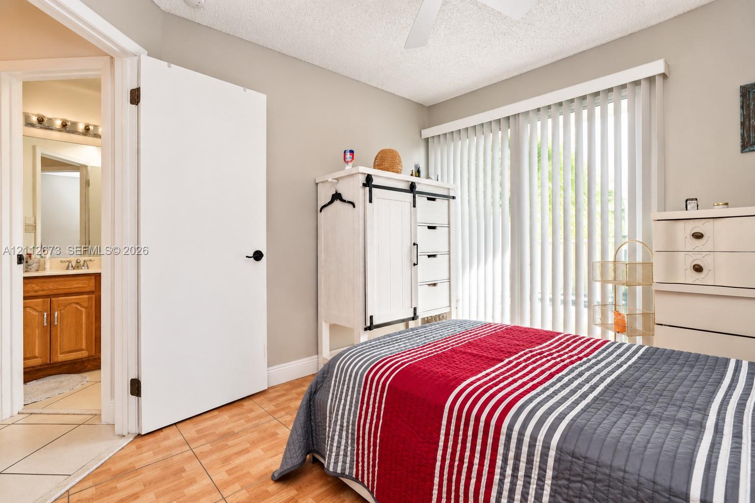 Room featuring ceramic tile flooring, neutral wall paint, vertical window blinds, and a white ceiling fan