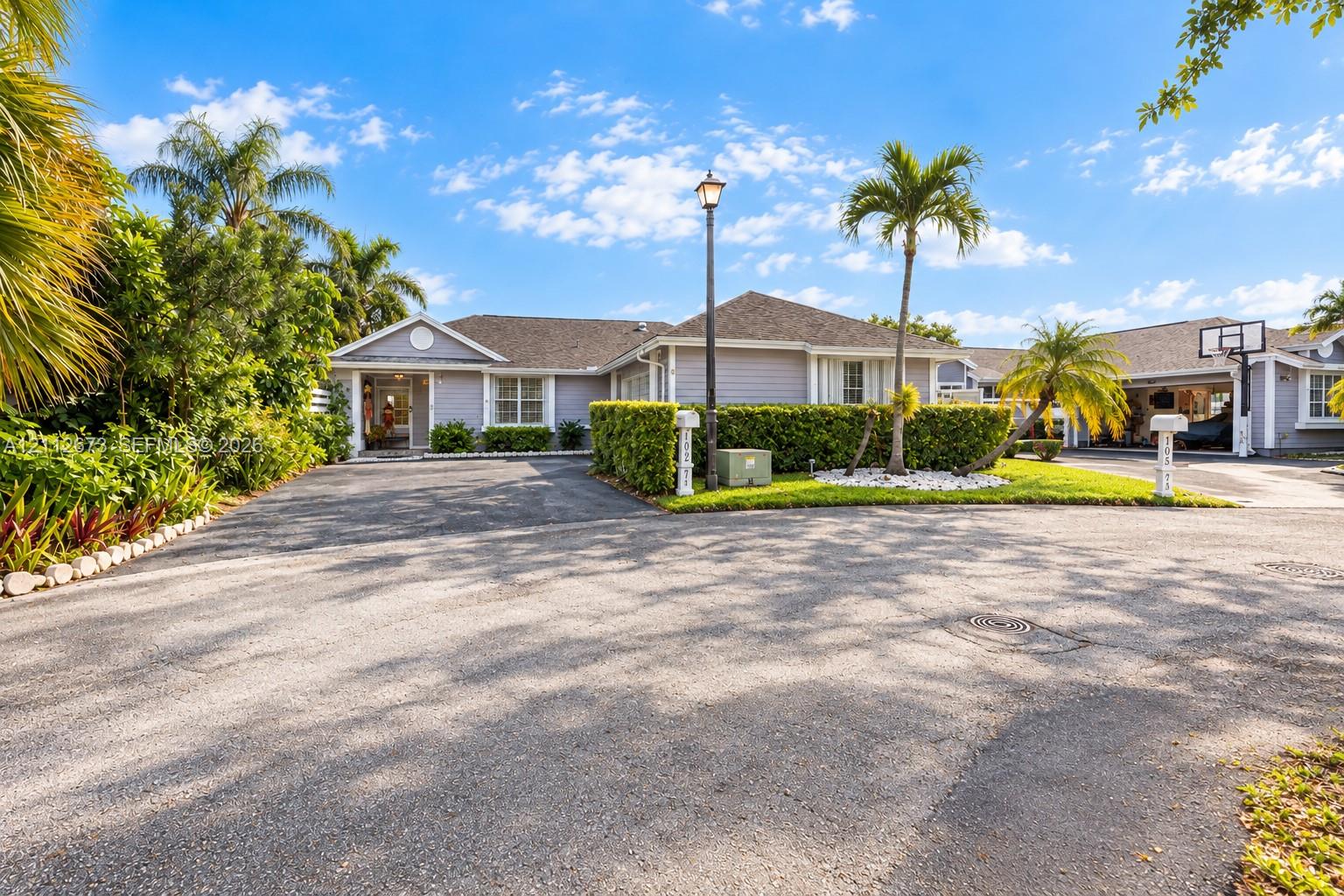 Exterior facade featuring horizontal siding, a pitched roof, expansive paved driveway, integrated carport, and manicured landscaping Exterior facade featuring horizontal siding, a pitched roof, expansive paved driveway, integrated carport, and manicured landscaping