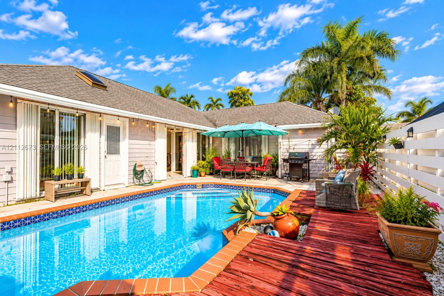 In-ground swimming pool with tile border, wood-finish decking, and privacy fencing In-ground swimming pool with tile border, wood-finish decking, and privacy fencing