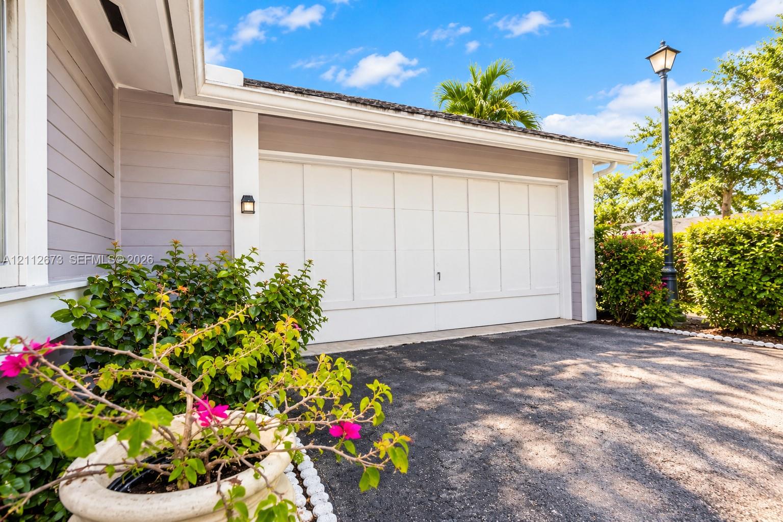 Exterior featuring horizontal siding, multi-panel garage door, attached wall-mounted light fixture, and paved driveway Exterior featuring horizontal siding, multi-panel garage door, attached wall-mounted light fixture, and paved driveway