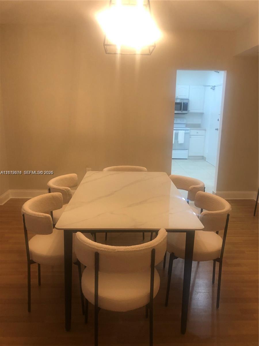 Dining area featuring wood-finish flooring and a geometric pendant light fixture Dining area featuring wood-finish flooring and a geometric pendant light fixture