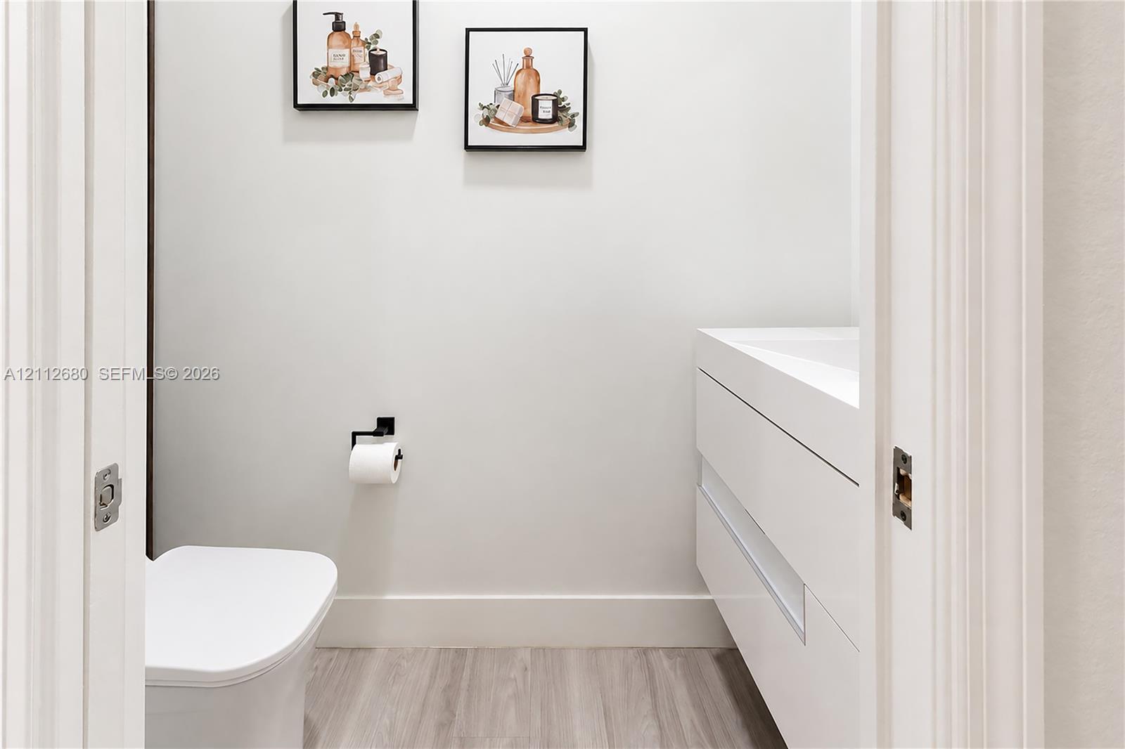 Floating vanity with integrated sink, wood-finish flooring, and matte black hardware