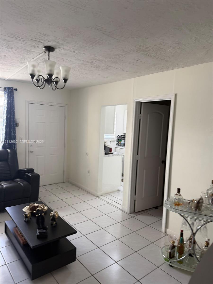 Interior featuring large-format ceramic tile flooring, five-light iron chandelier, and neutral wall tones