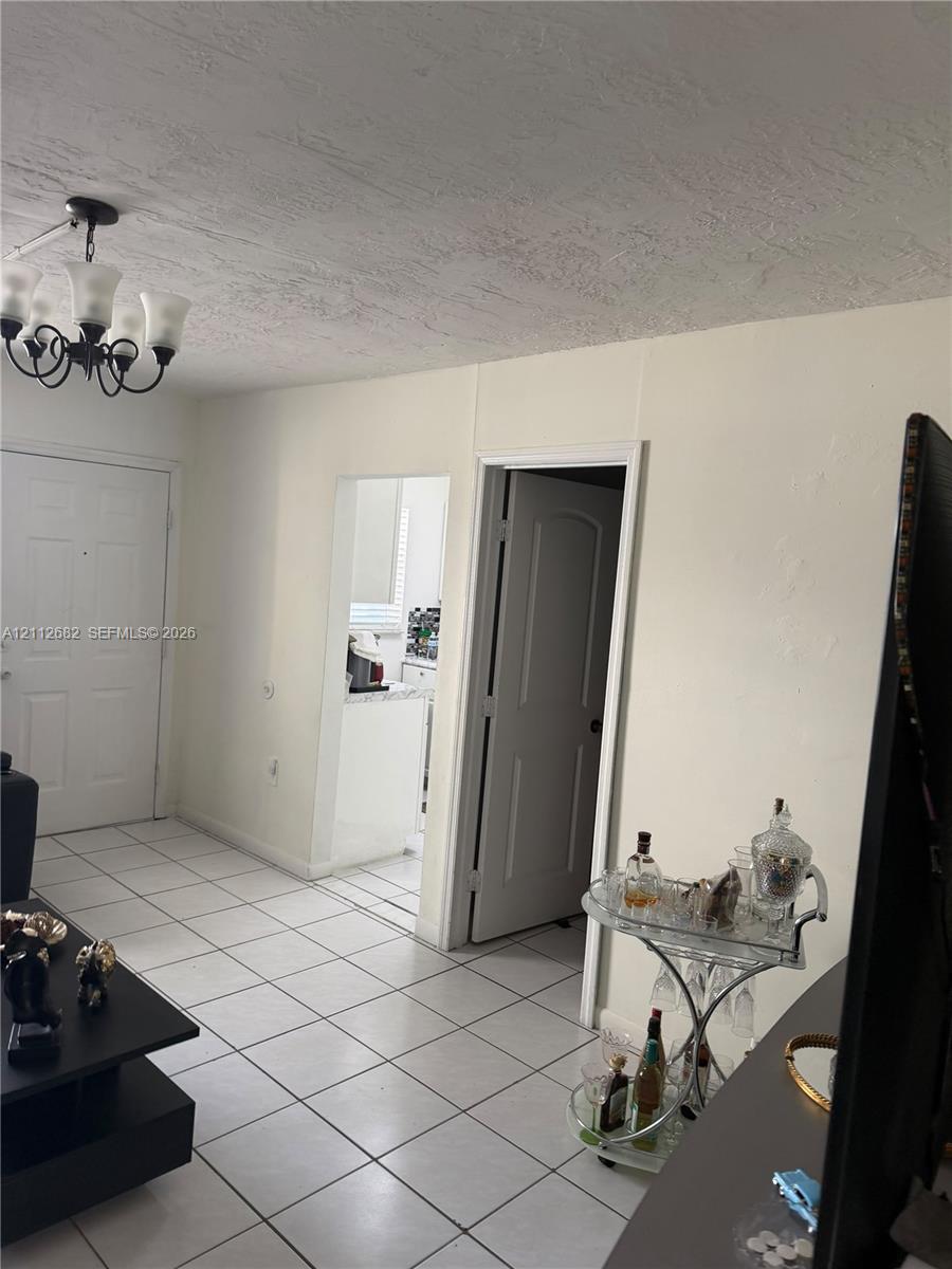 Interior space featuring tile flooring, six-panel interior doors, and a decorative multi-arm chandelier