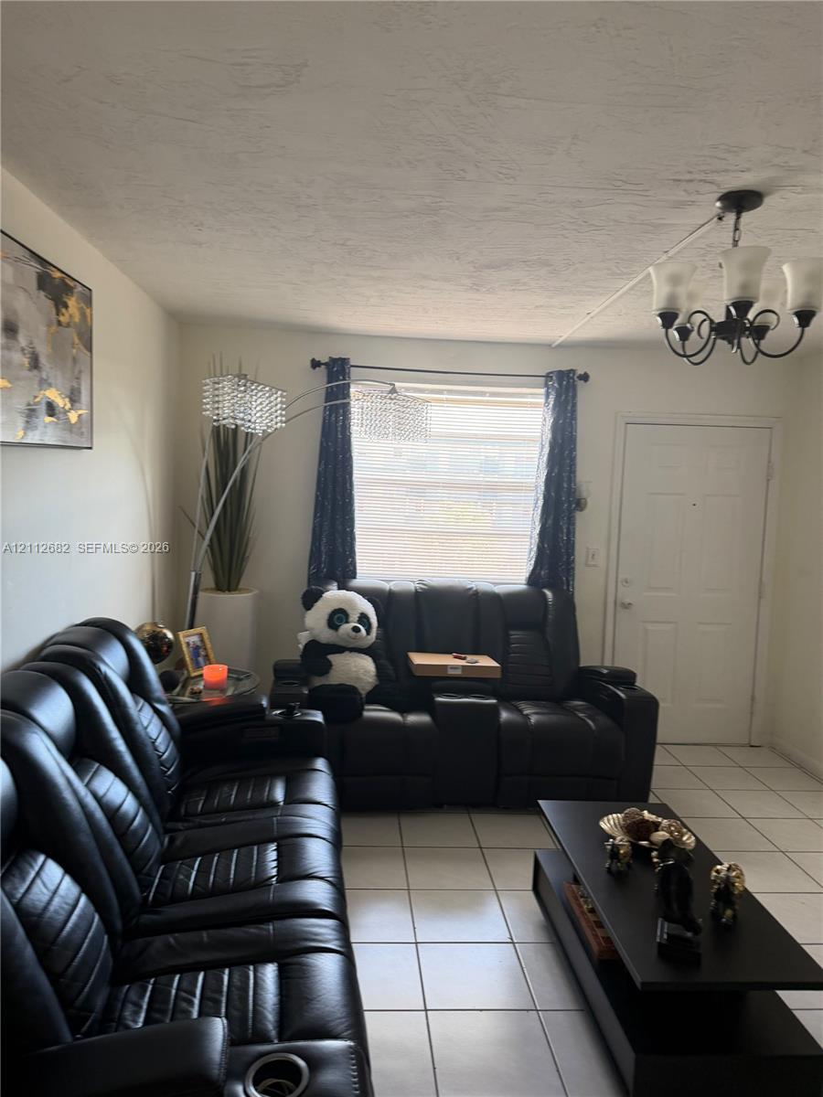 Room featuring white tile flooring, a multi-arm chandelier with frosted glass shades, and a large window
