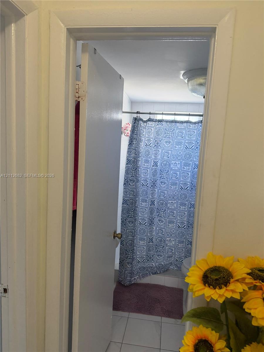 Enclosed room featuring a neutral-toned door, white-framed doorway, and tile flooring