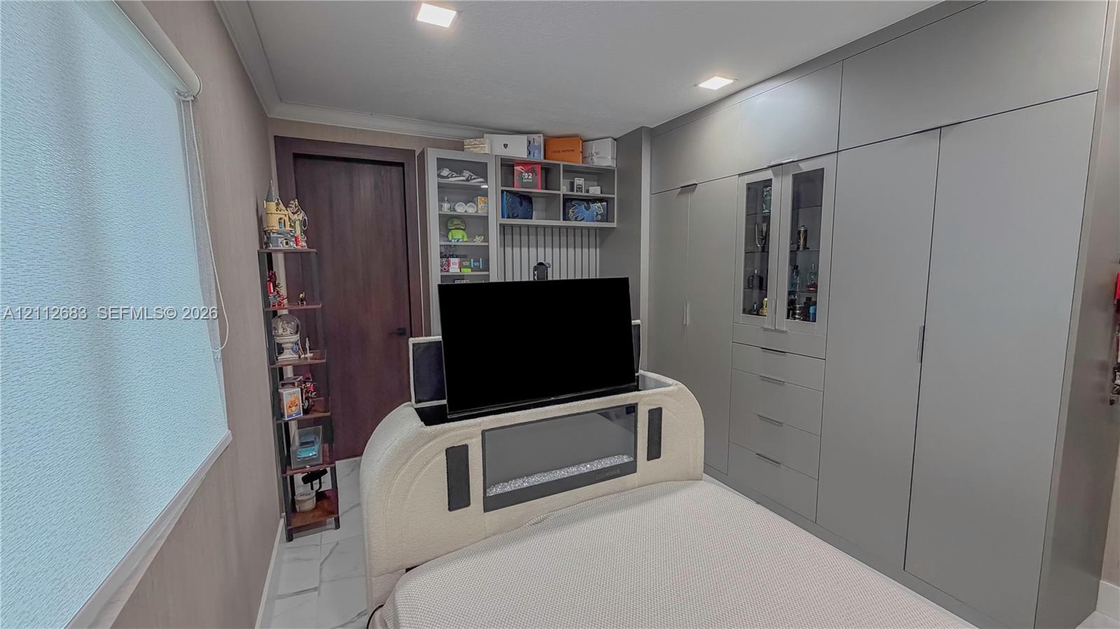 Built-in full-height cabinetry with integrated shelving, flush-panel doors, and recessed lighting