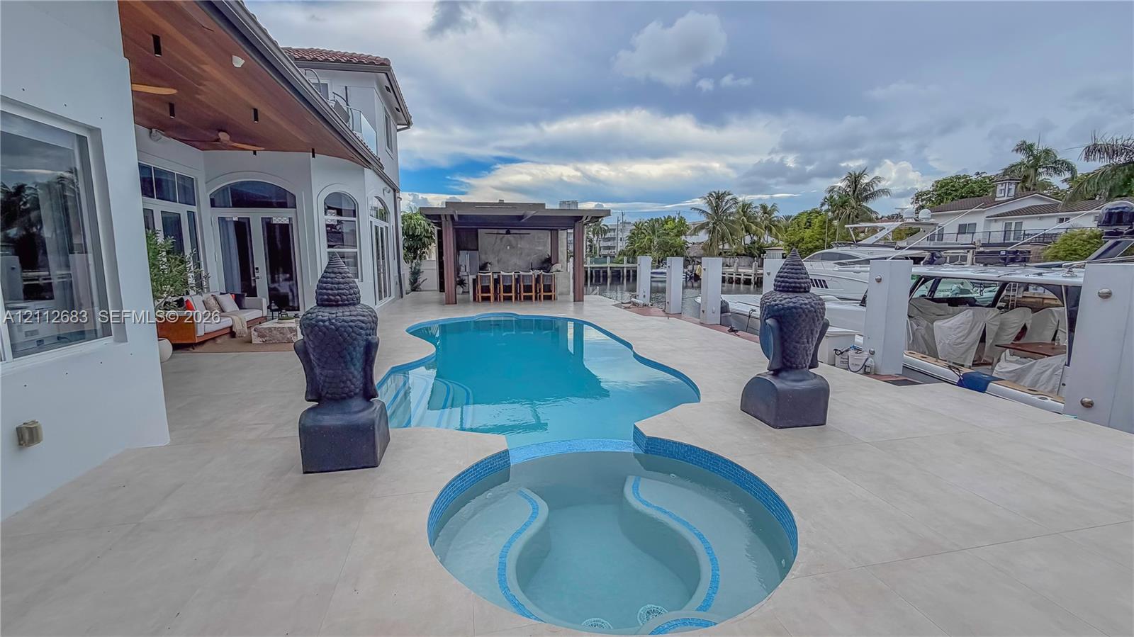 Outdoor terrace featuring an in-ground swimming pool, integrated spa, covered waterfront patio, and wood-finish ceiling treatment