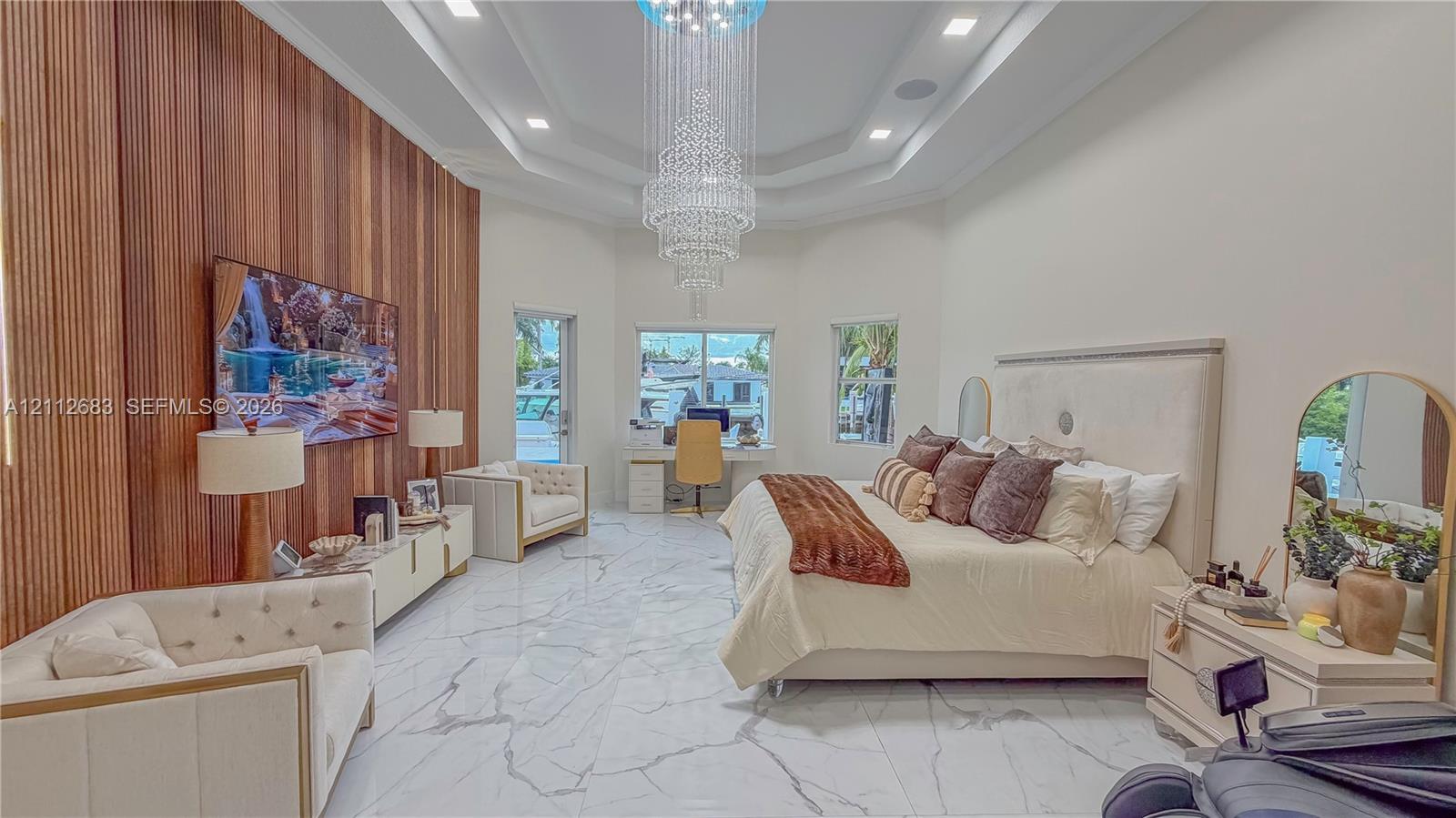 Interior space featuring a vaulted ceiling with recessed lighting, a multi-tiered crystal chandelier, stone-finish tile flooring, and a vertical wood-slat accent wall