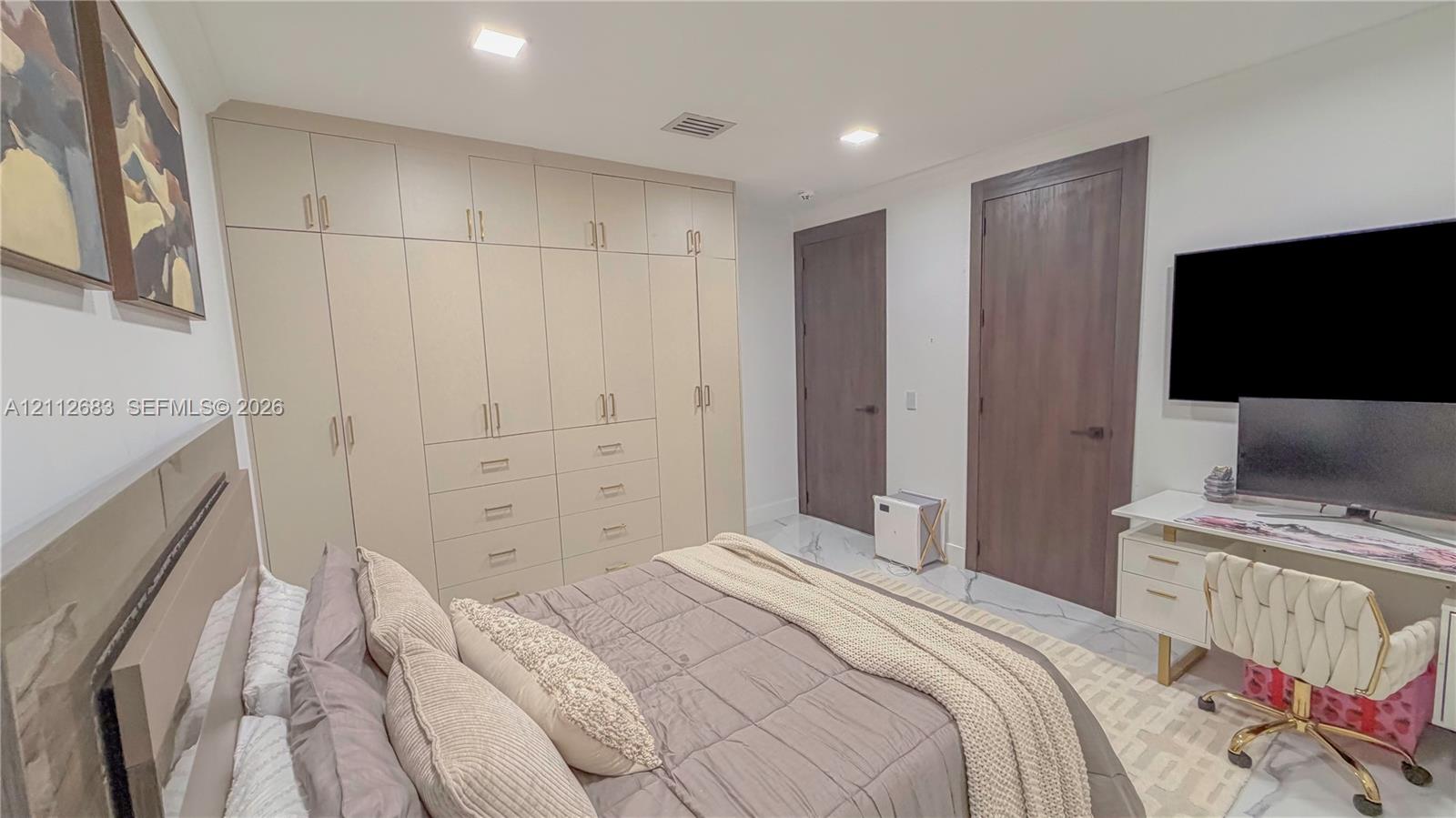 Custom floor-to-ceiling built-in cabinetry featuring integrated drawer storage, contrasting dark-stained wood doors, recessed ceiling lighting, and polished stone-finish flooring