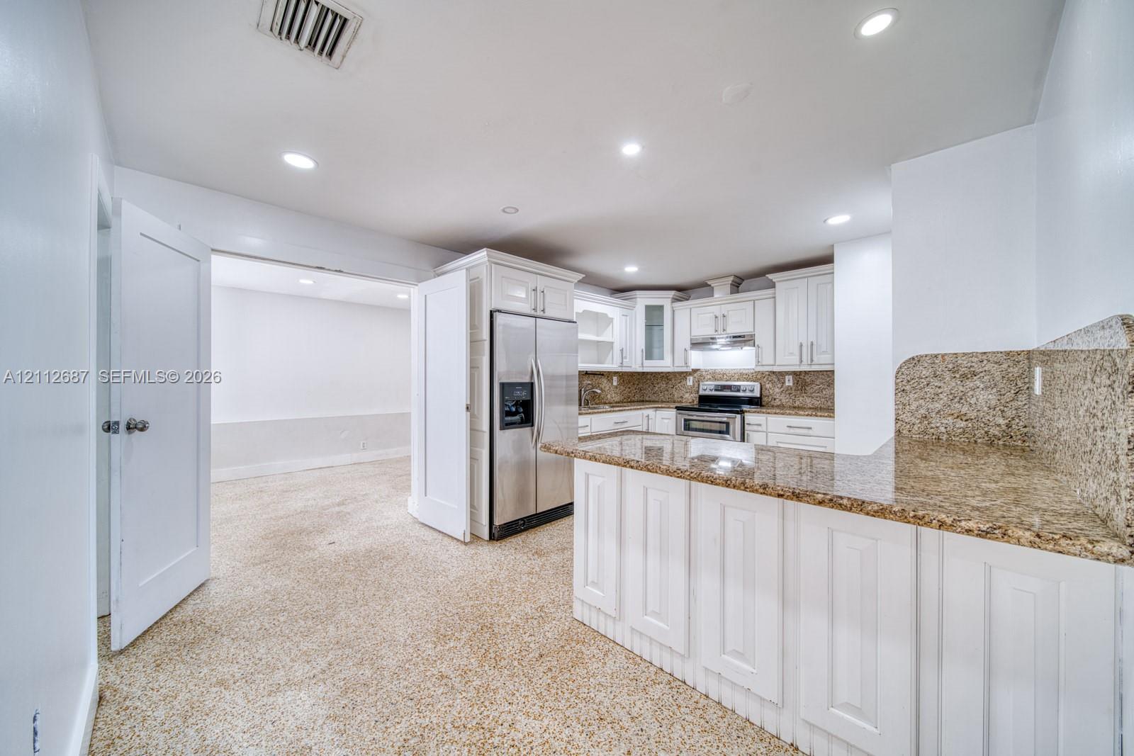 Kitchen featuring white cabinetry, stone-surface countertops, recessed lighting, and stainless steel appliances