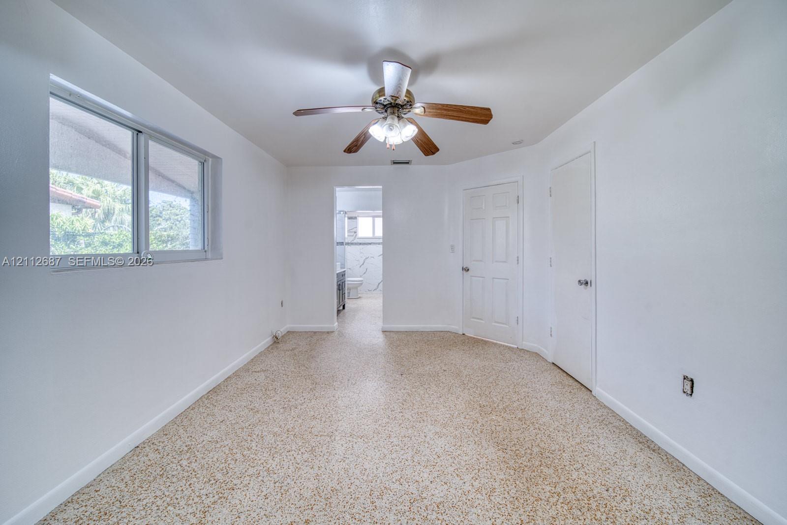 Interior space featuring neutral wall paint, terrazzo flooring, a ceiling fan with integrated lighting, and two six-panel interior doors