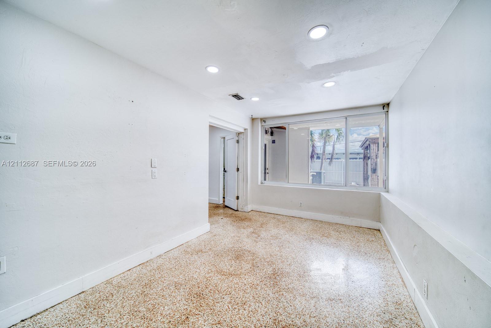 Interior space featuring terrazzo flooring, recessed ceiling lighting, and a multi-panel sliding window