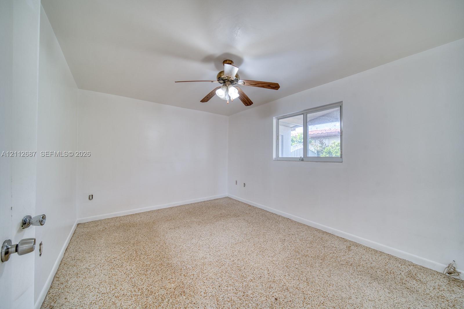 Room featuring neutral wall finishes, carpeting, a ceiling-mounted light fixture with a fan, and a single-pane sliding window