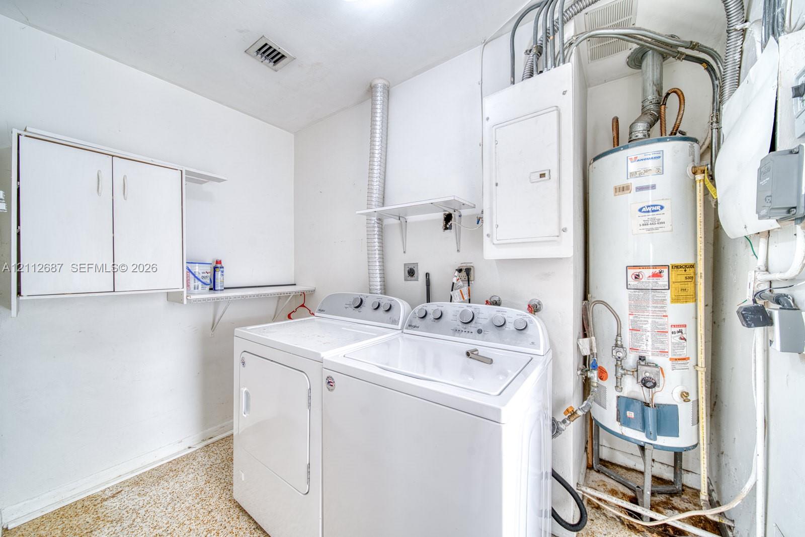 Utility area featuring white wall-mounted cabinetry, integrated open shelving, and a dedicated tank-style water heater