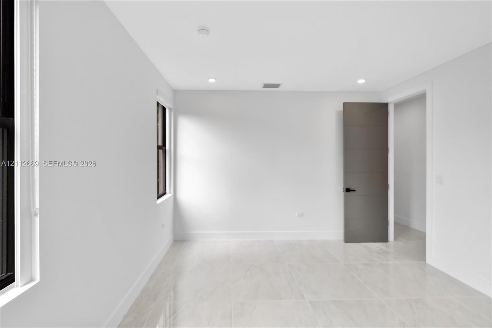 Interior space featuring large-format stone-finish tile flooring, neutral walls, recessed LED lighting, and a multi-panel door with matte black hardware