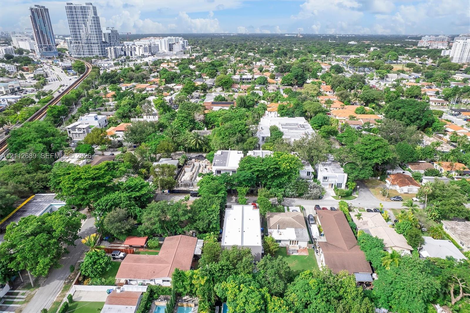Aerial perspective featuring dense canopy coverage, established residential infrastructure, and proximity to metropolitan high-rise development