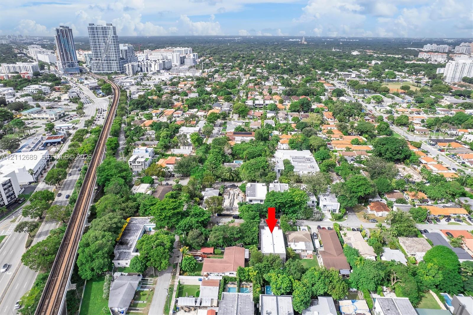 Aerial perspective of a detached residential property situated in a dense, tree-lined neighborhood
