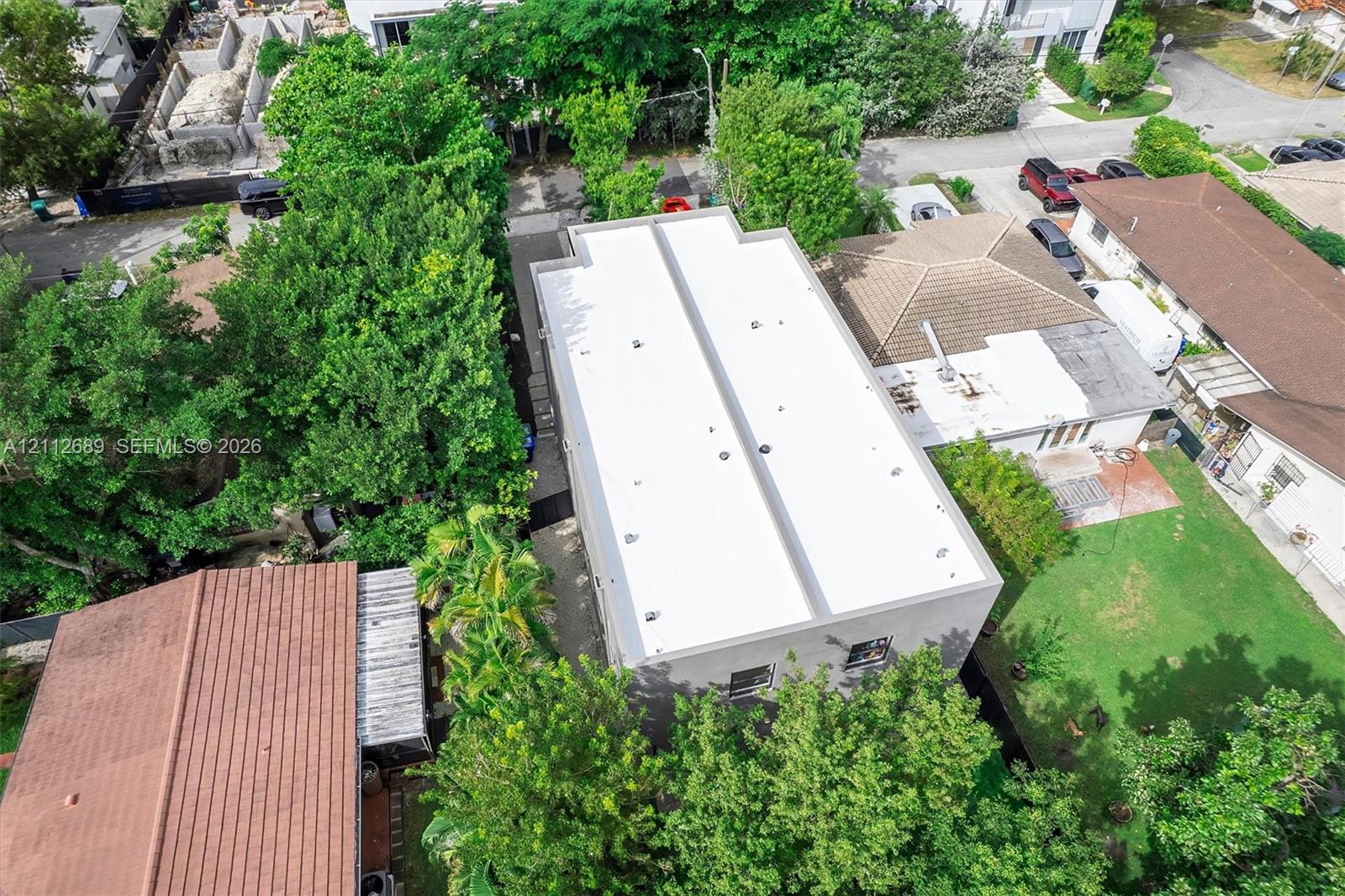 Aerial perspective featuring a flat roof structure surrounded by mature canopy trees and established landscaping