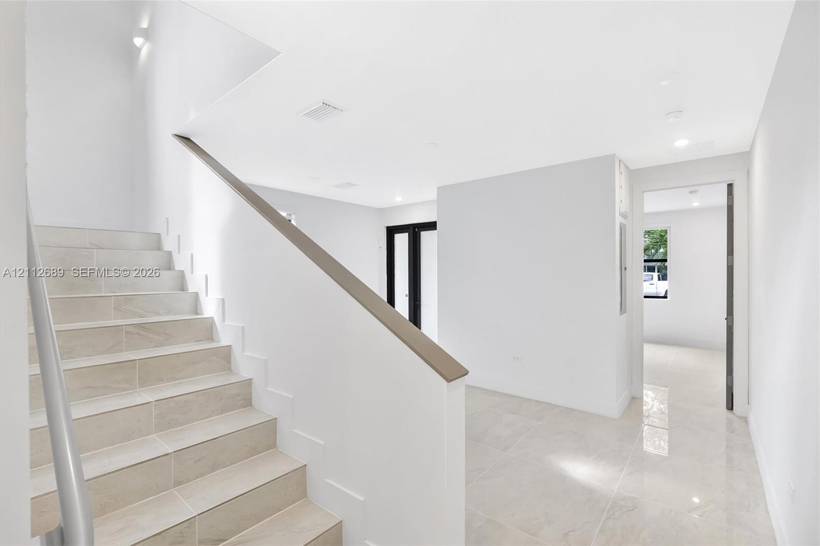 Staircase with tile-finished treads and a sleek handrail, polished tile flooring, and recessed ceiling lighting