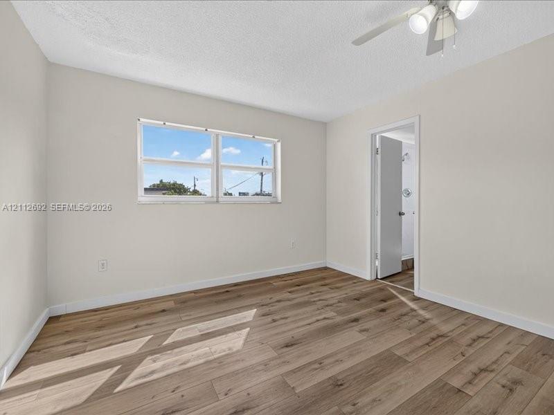 Neutral interior featuring wood-finish flooring, white walls, a dual-pane horizontal sliding window, and a white ceiling fan with integrated lighting