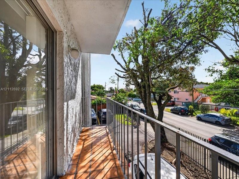 Private balcony featuring terracotta tile flooring, metal railing, and stucco exterior wall