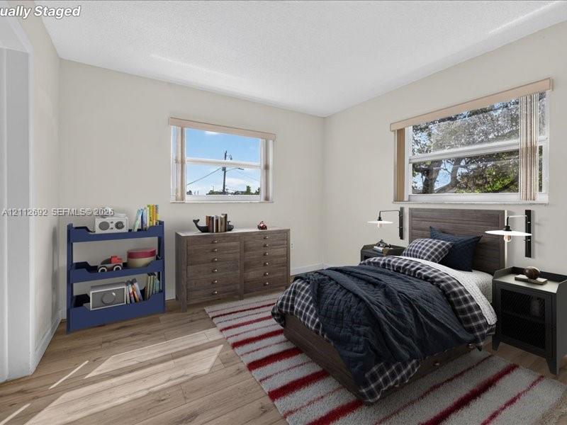 Wood-finish flooring, dual windows with neutral-tone blinds, and wall-mounted swing-arm light fixtures