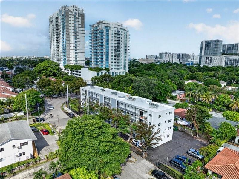 Multi-story residential building featuring a white facade, private balconies, and dedicated asphalt surface parking