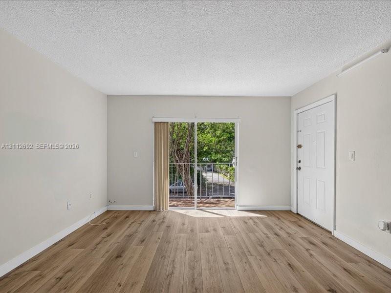 Living area featuring wood-finish flooring, neutral wall paint, and sliding glass doors with access to an exterior balcony