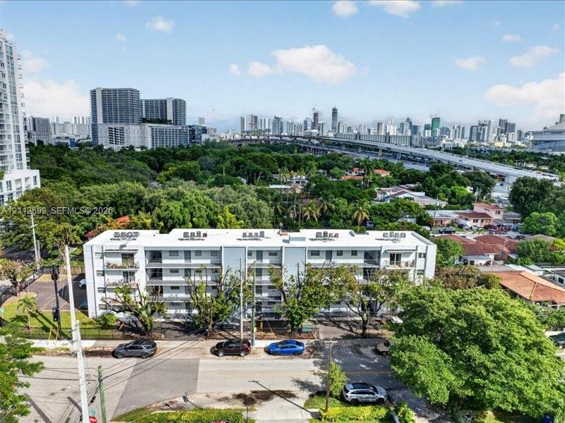 Multi-story residential building featuring a flat roofline, neutral exterior cladding, integrated recessed balconies, and dedicated surface parking