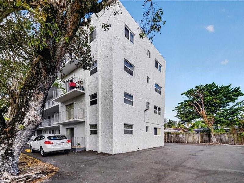 Multi-story stucco exterior featuring private balconies with metal railings and paved surface parking