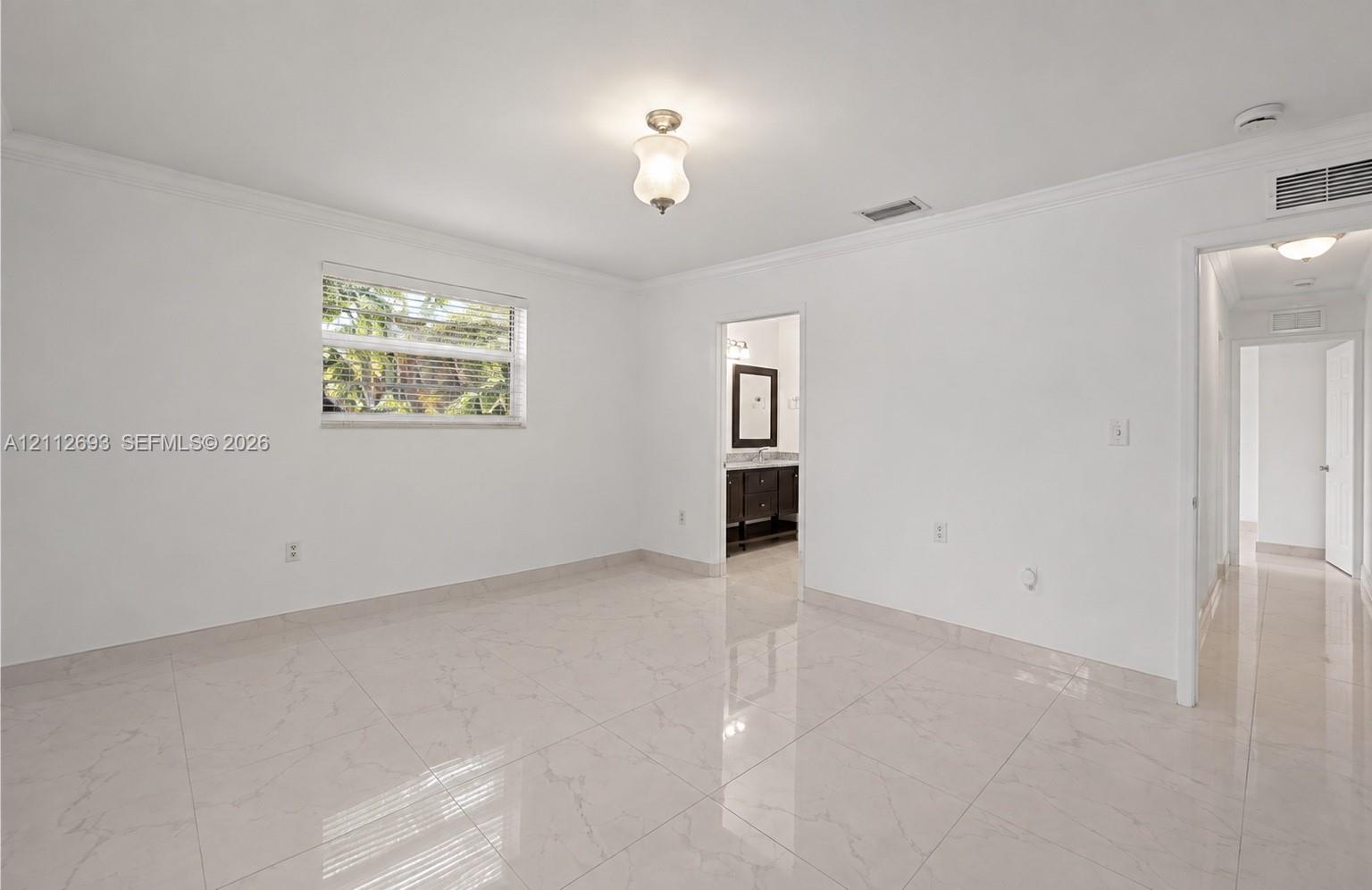 Interior space featuring polished light-toned tile flooring, crown molding, a central glass-shaded light fixture, and a horizontal window