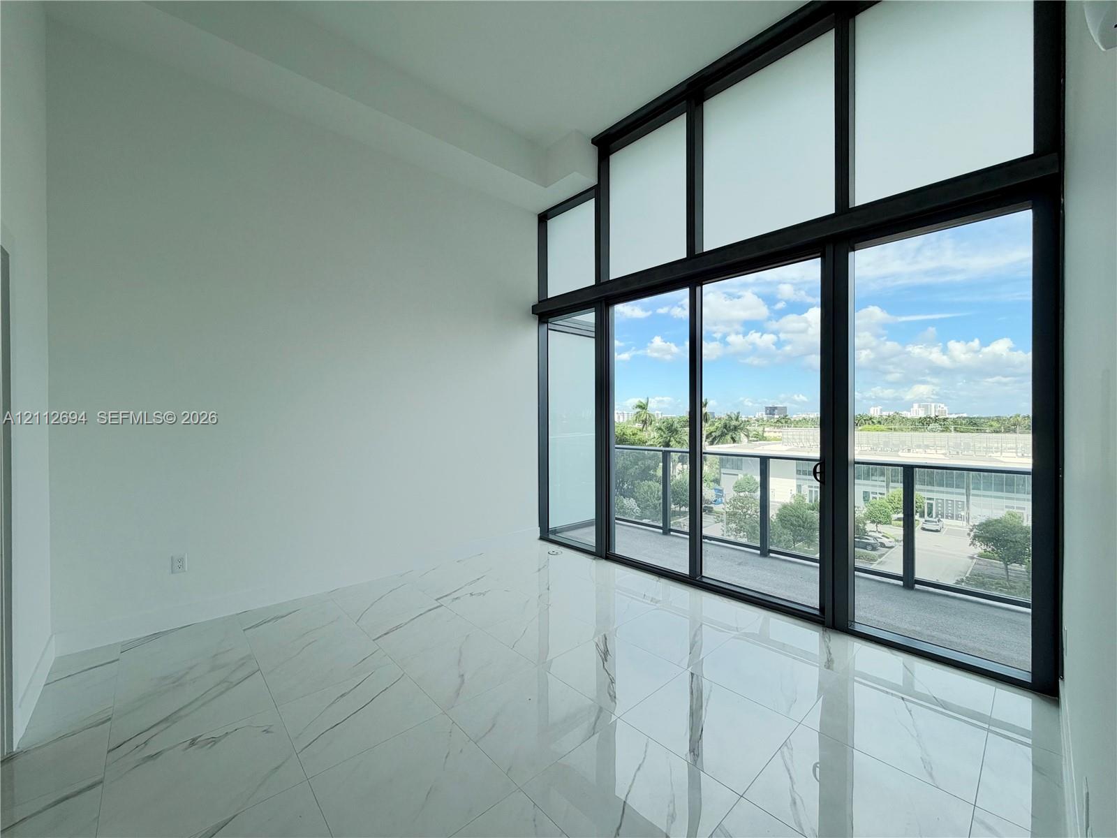 Floor-to-ceiling windows with black metal framing, polished white tile flooring, and integrated glass balcony door Floor-to-ceiling windows with black metal framing, polished white tile flooring, and integrated glass balcony door