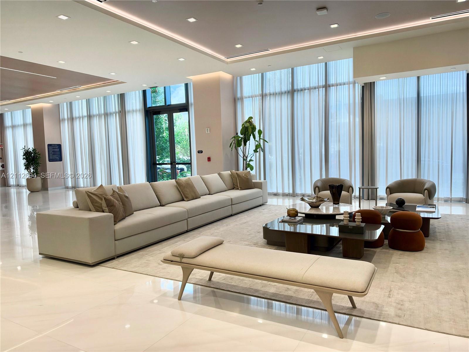 Expansive common area featuring floor-to-ceiling windows, polished tile flooring, recessed cove lighting, and drop ceiling details