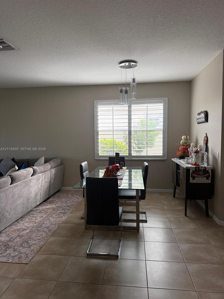 Ceramic tile flooring, multi-pane window with plantation shutters, and a three-light glass pendant fixture Ceramic tile flooring, multi-pane window with plantation shutters, and a three-light glass pendant fixture