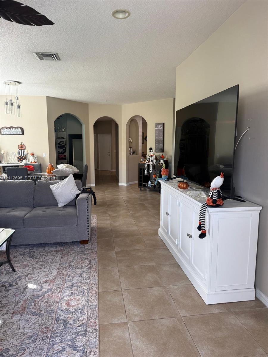 Open-concept interior featuring large-format neutral tile flooring and distinctive arched architectural entryways Open-concept interior featuring large-format neutral tile flooring and distinctive arched architectural entryways