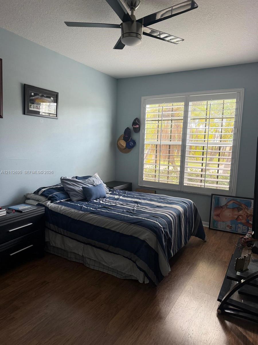 Wood-finish flooring, plantation shutters, and a multi-blade ceiling fan with integrated lighting
