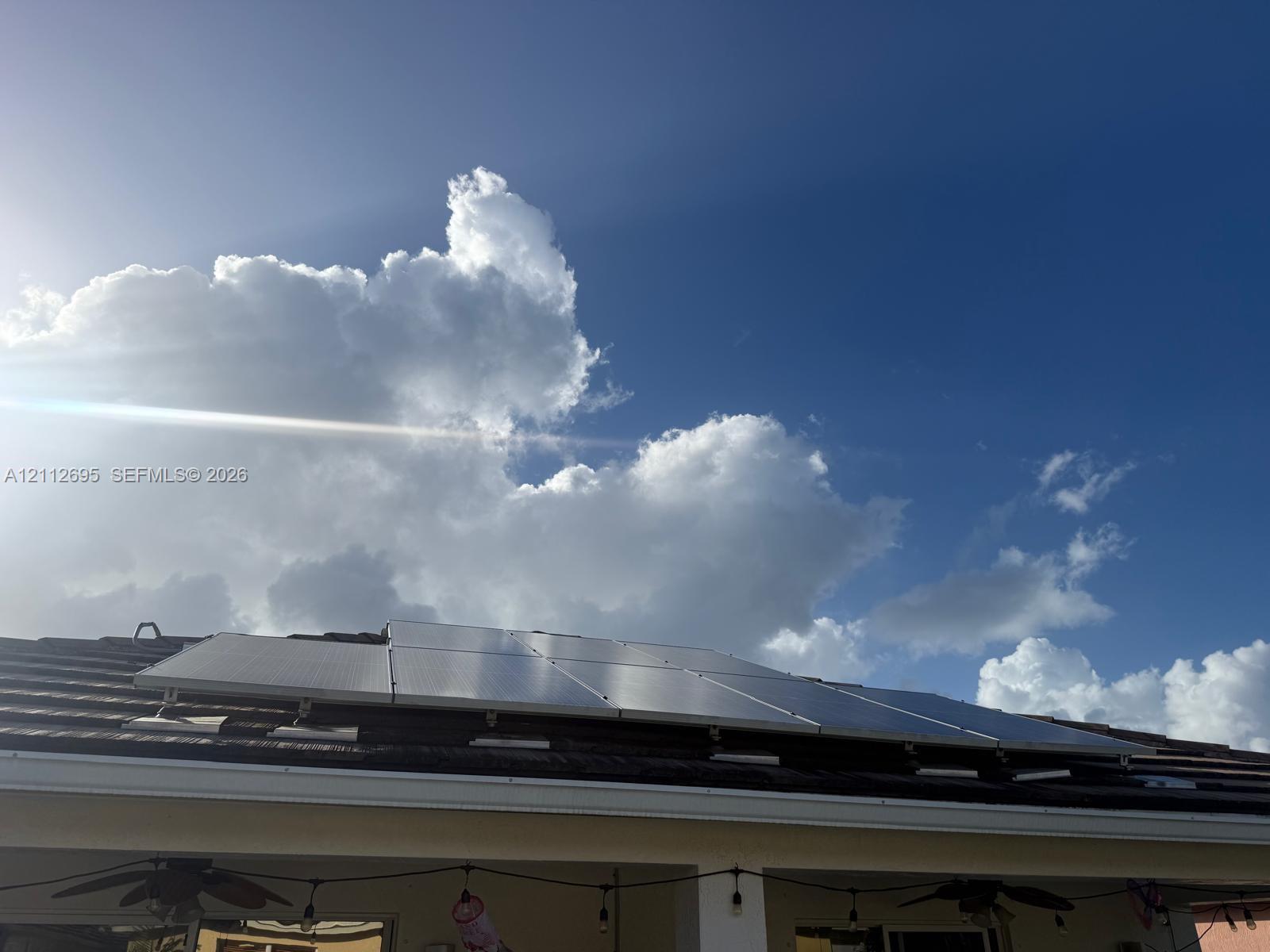 Rooftop solar panel array mounted on a tile roof, including a covered patio area with dual ceiling fans