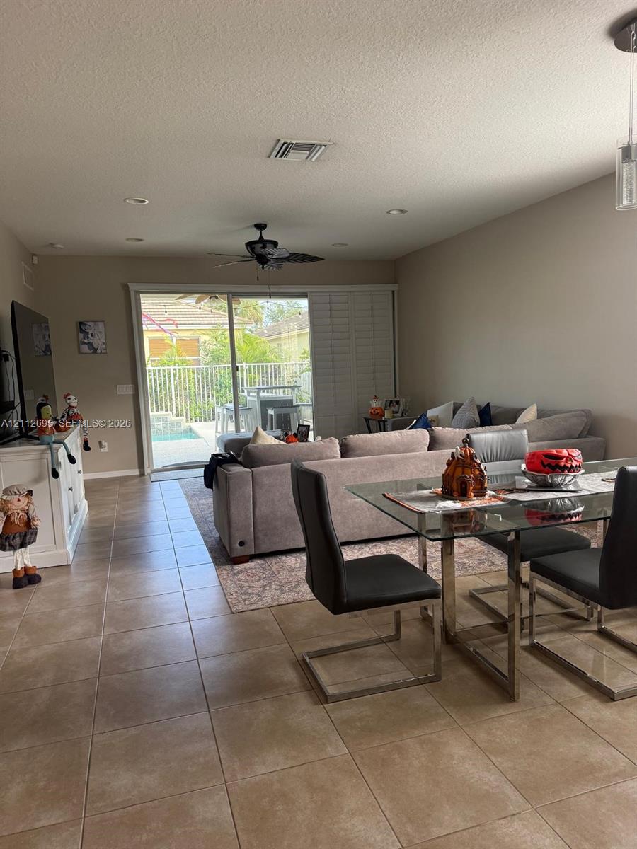 Large-format tile flooring, recessed lighting, ceiling fan, and sliding glass doors with access to a fenced outdoor area Large-format tile flooring, recessed lighting, ceiling fan, and sliding glass doors with access to a fenced outdoor area