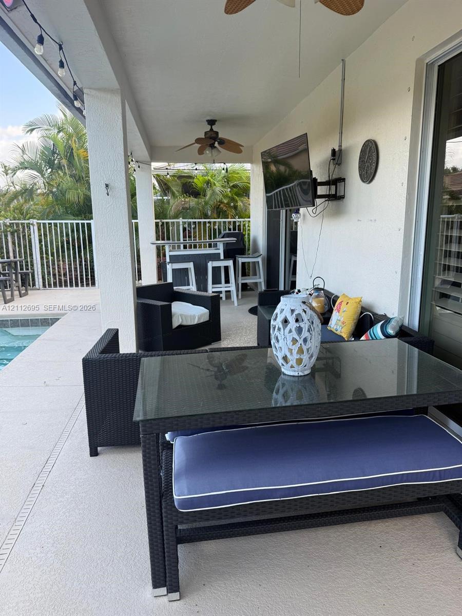 Covered patio featuring a concrete deck, dual ceiling fans, recessed lighting, and a white metal perimeter fence