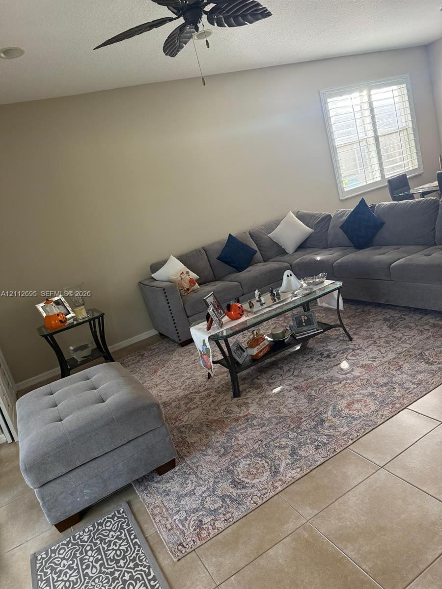 Neutral wall palette featuring large-format tile flooring, plantation shutters, and a ceiling-mounted fan with integrated lighting
